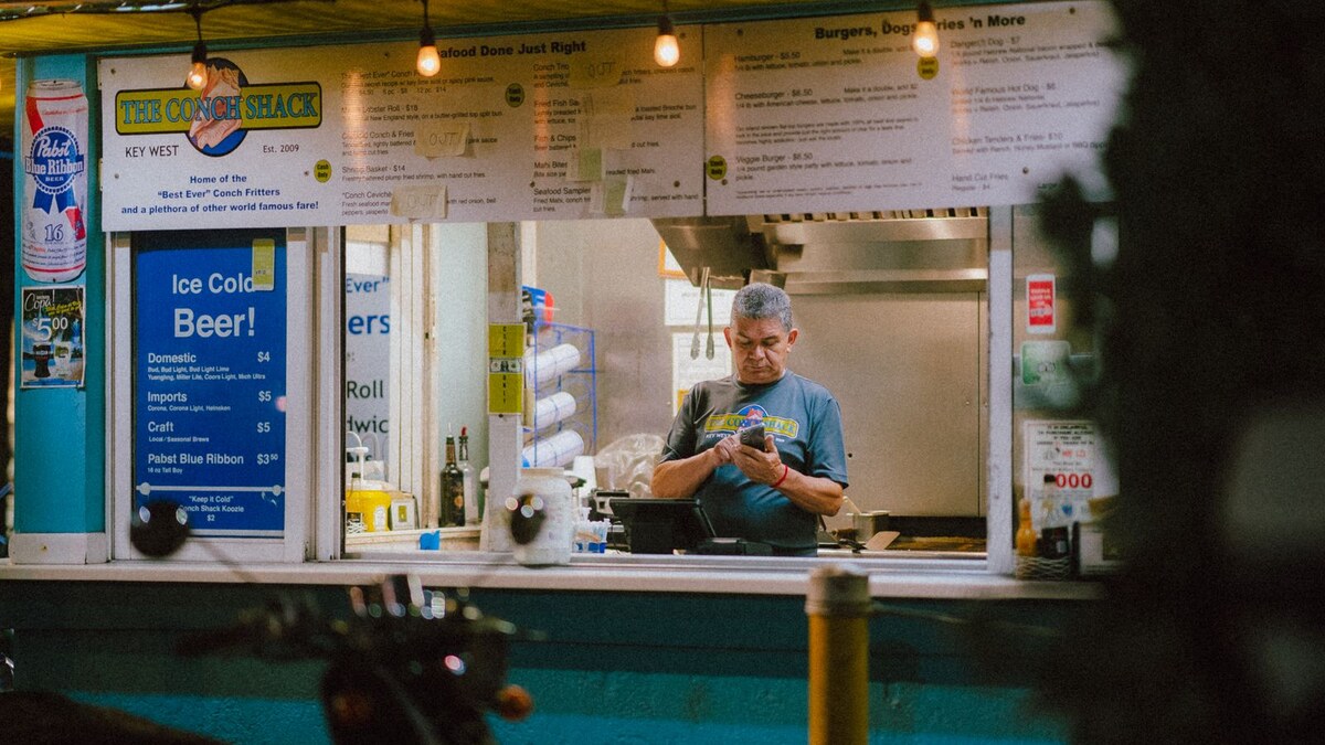 Local shop operator checking a phone behind a Key West storefront counter